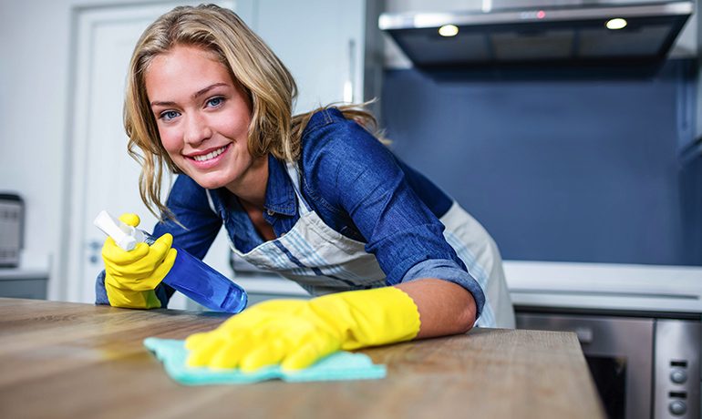 Schoonmaakmedewerker reinigt een werkblad met reinigingsmiddel